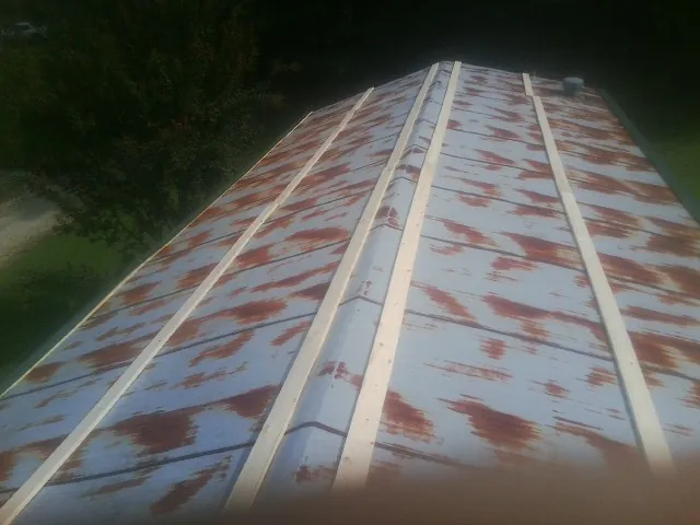 Rusted metal roof panels with new wood purlins before replacement — Storm Damage Roof Repair in Carolina Beach by Roofing Brothers