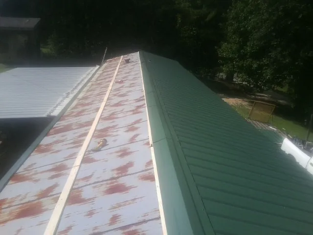 Old rusted panels beside newly installed green metal roofing — Wind Damage Roof Repair by Roofing Brothers in Carolina Beach