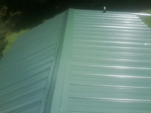 New green metal panels meeting at the ridge of a roof — Flat Roof Repair work by our crew in Carolina Beach