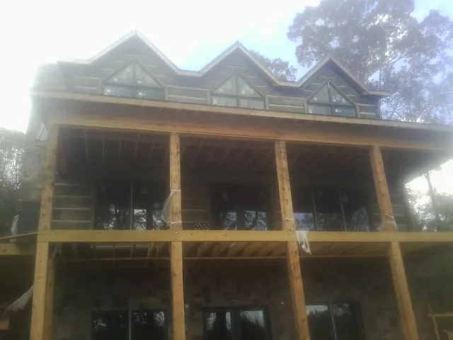 Dormers and porch framing on a large log home under construction — Roof Coating work by our crew in Carolina Beach
