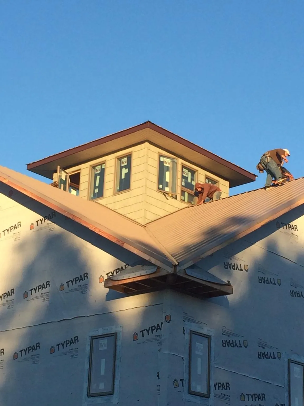 Roofers working around a rooftop cupola on a new metal roof at sunset — Roof Waterproofing in Carolina Beach by Roofing Brothers